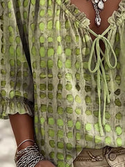Close view of lime green spotted blouse with ruffled neckline and tie