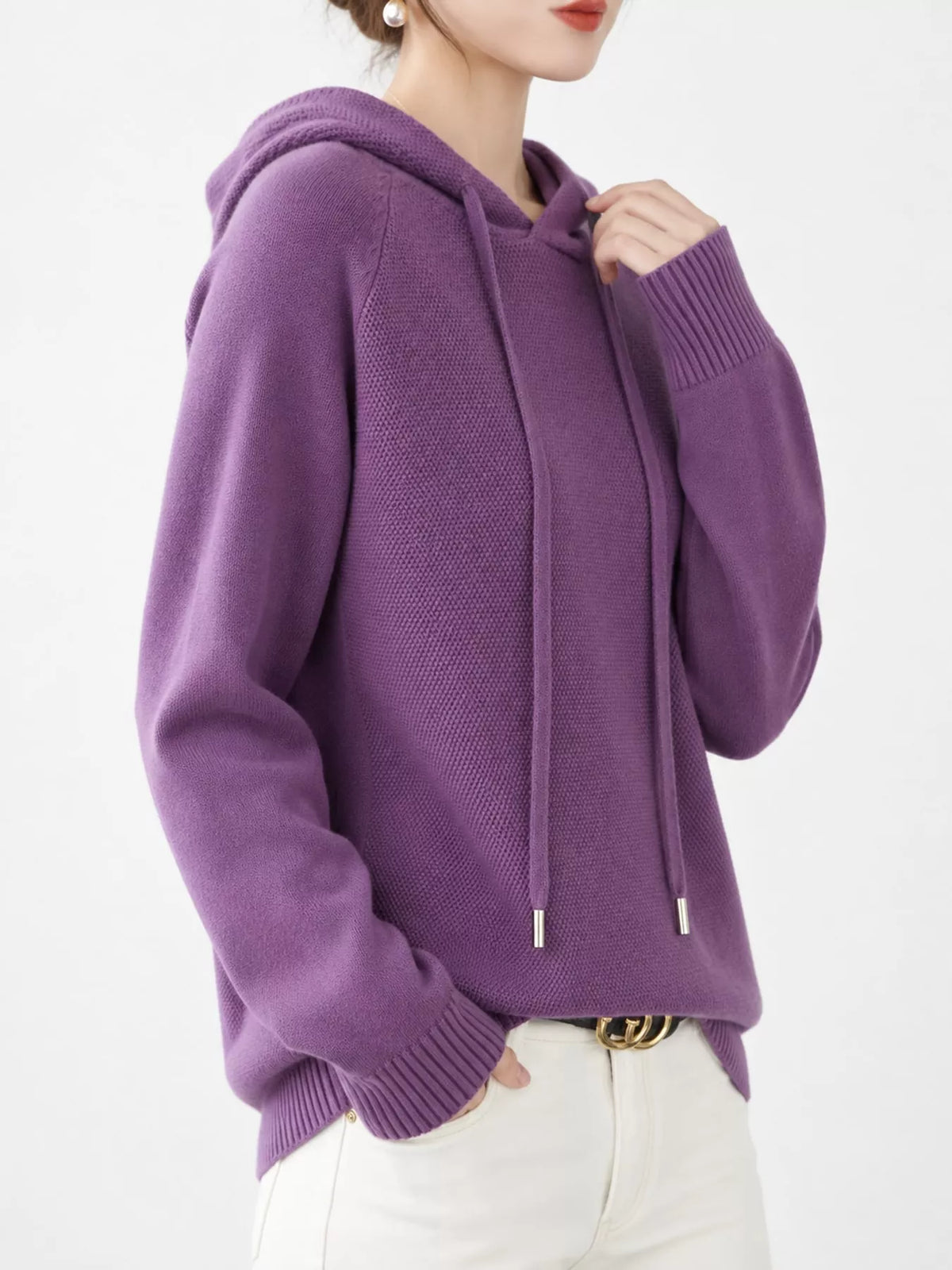 Angled view of the purple hooded sweater with one hand near the neckline.
