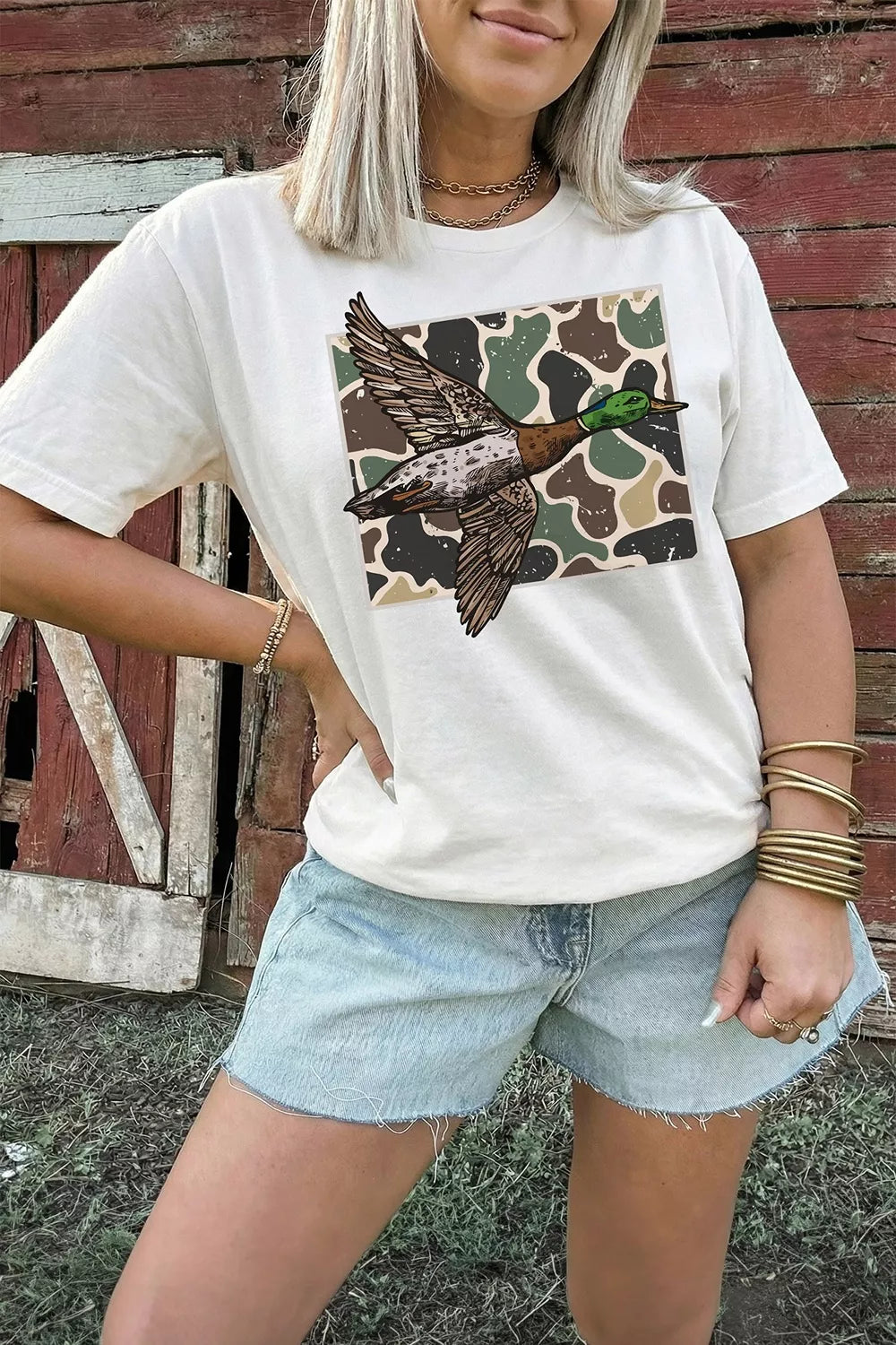 Model wearing white duck camo graphic tee with light denim shorts
