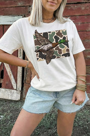 Model wearing white duck camo graphic tee with light denim shorts