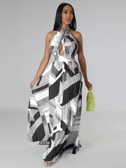Black-and-white pleated halter dress on a model holding the skirt beside a light green handbag.