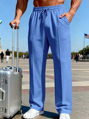 Front view of blue wide-leg pants with drawstring waist beside a suitcase.