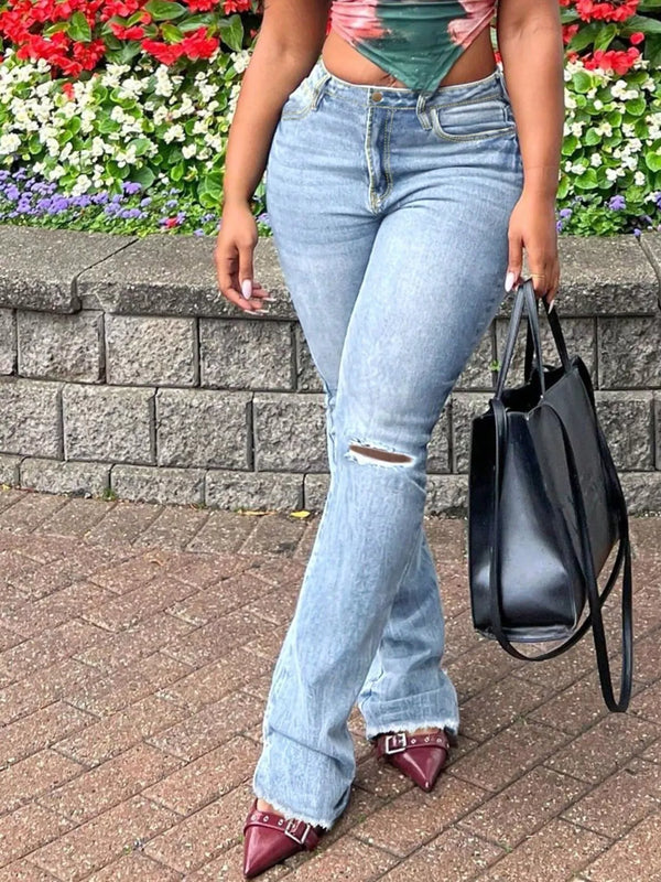Light blue ripped-knee flare jeans styled with a cropped top and black handbag.