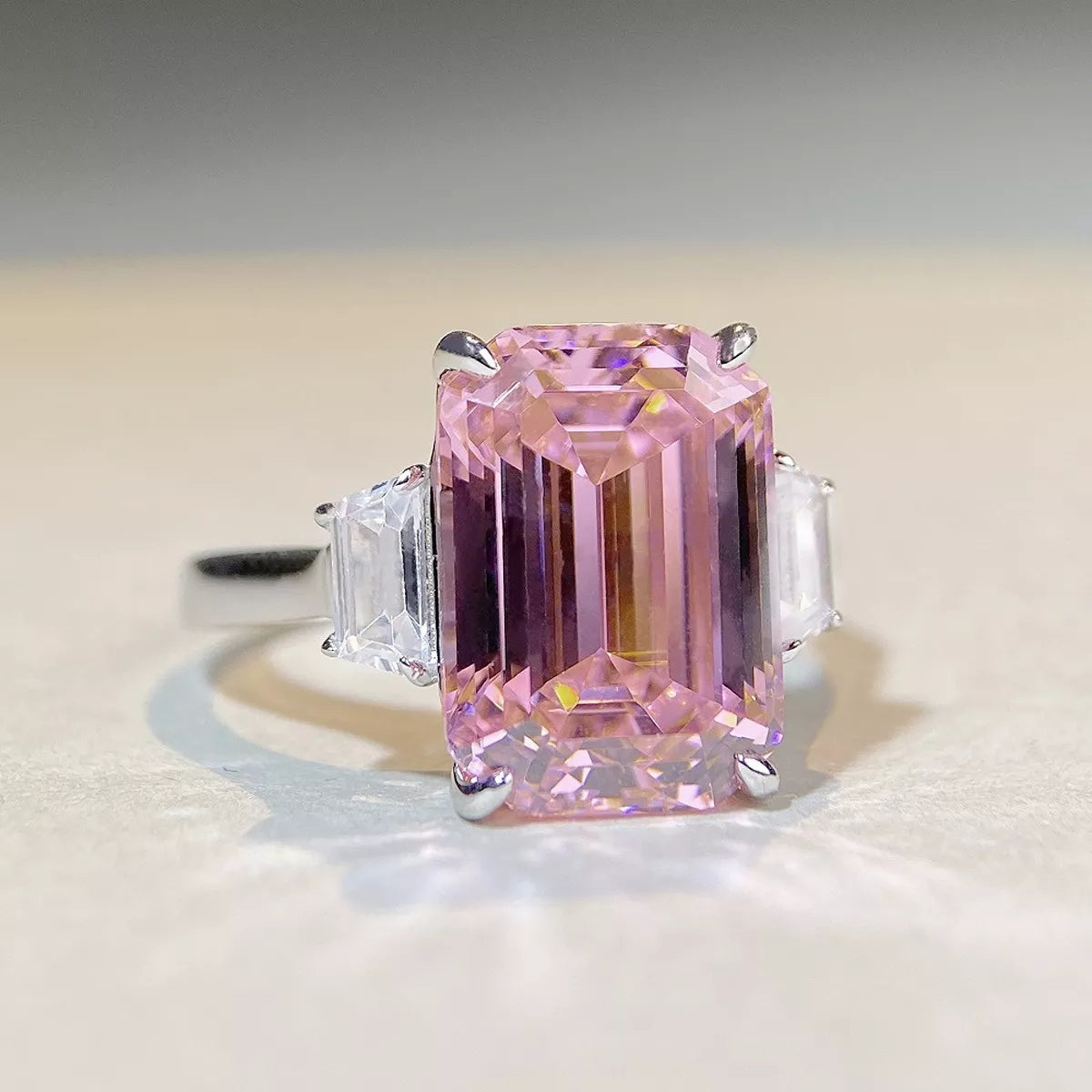 Front view of a rectangular faceted pink gemstone with clear side stones