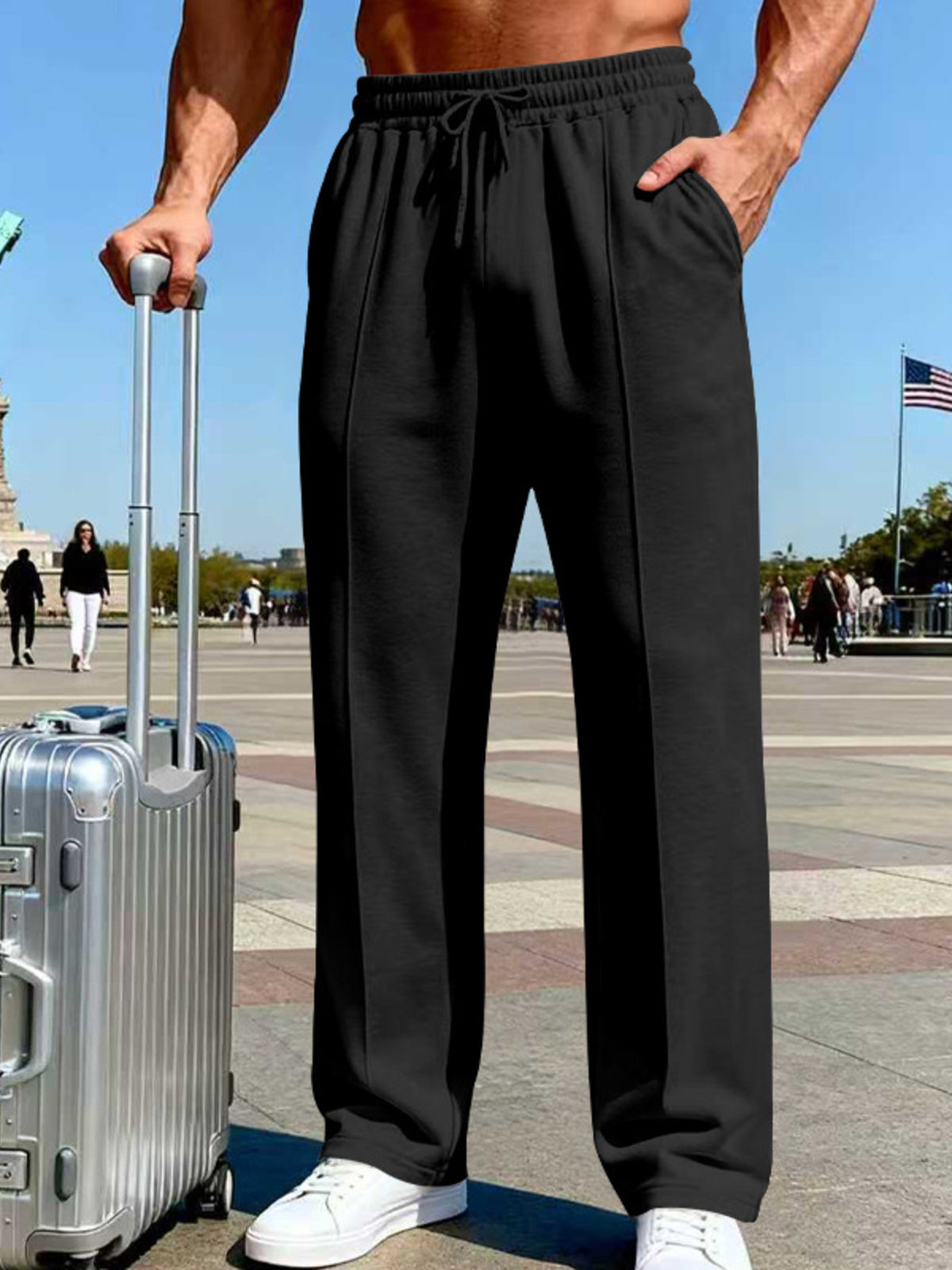 Angled view of light gray wide-leg drawstring pants beside a suitcase.