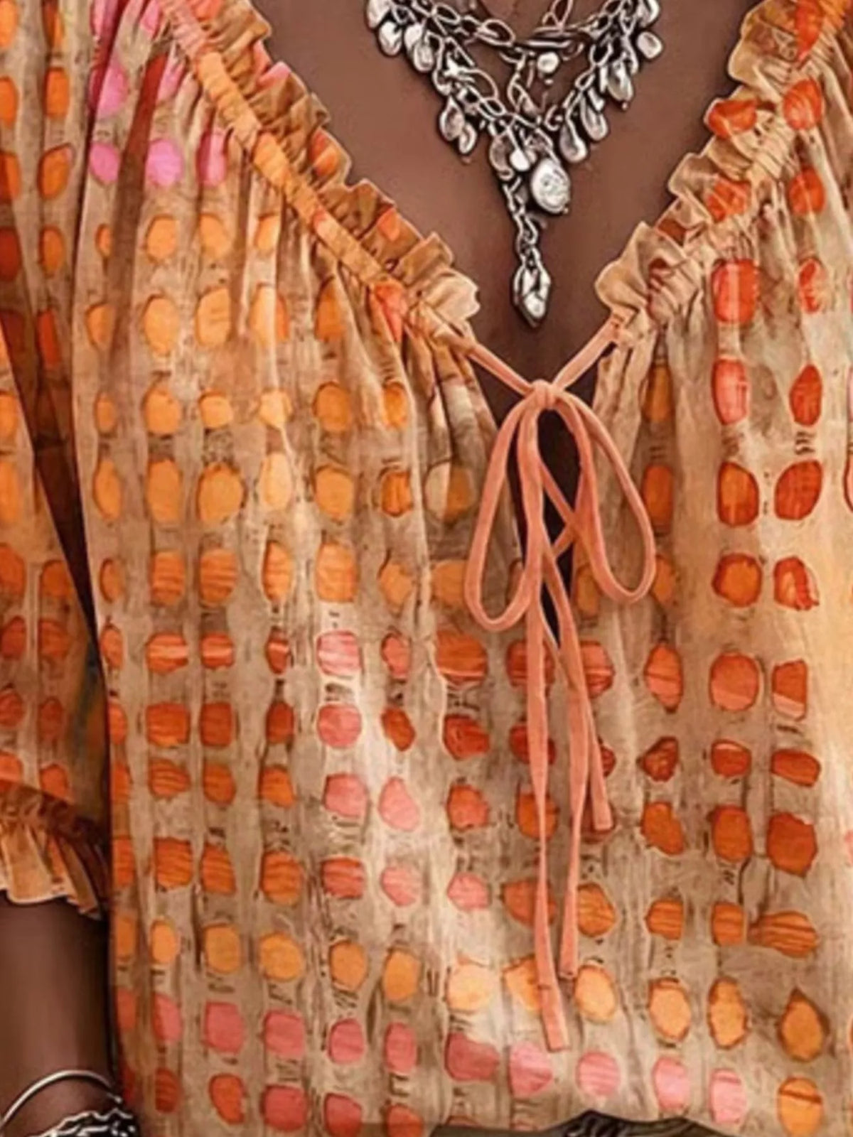 Close-up of orange spotted blouse showing ruffled neckline and front tie