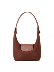Front view of the brown bag with the short handle and textured flap centered above the body.