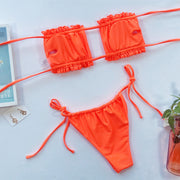 Orange bikini laid flat with the inside of its frill bandeau top and matching tie-side bottoms visible