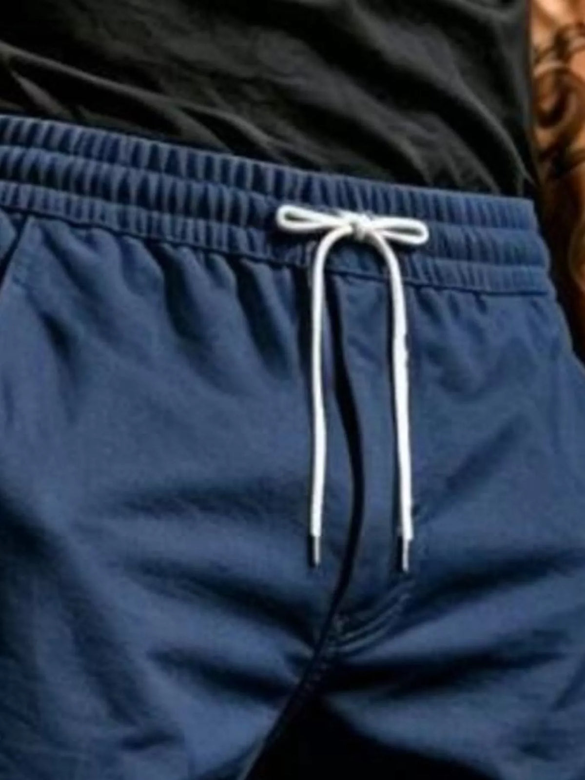 Close-up of navy joggers showing the gathered elastic waistband and tied white drawstring