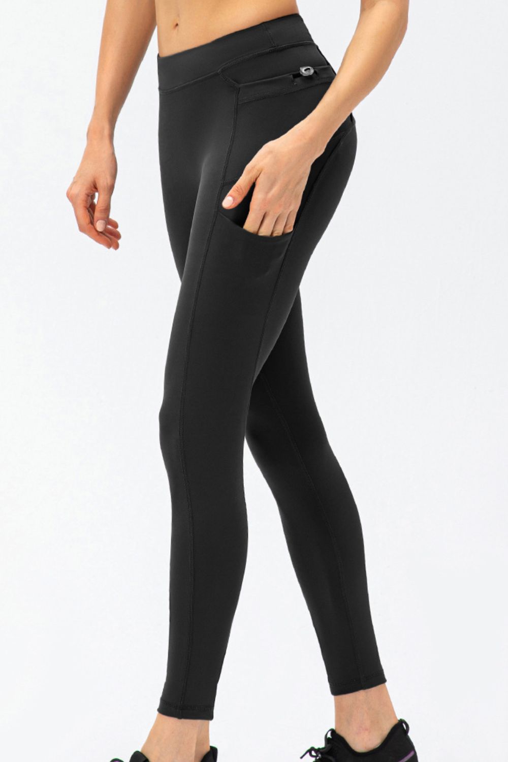 Model in black leggings lifting one leg to show the fitted full-length cut