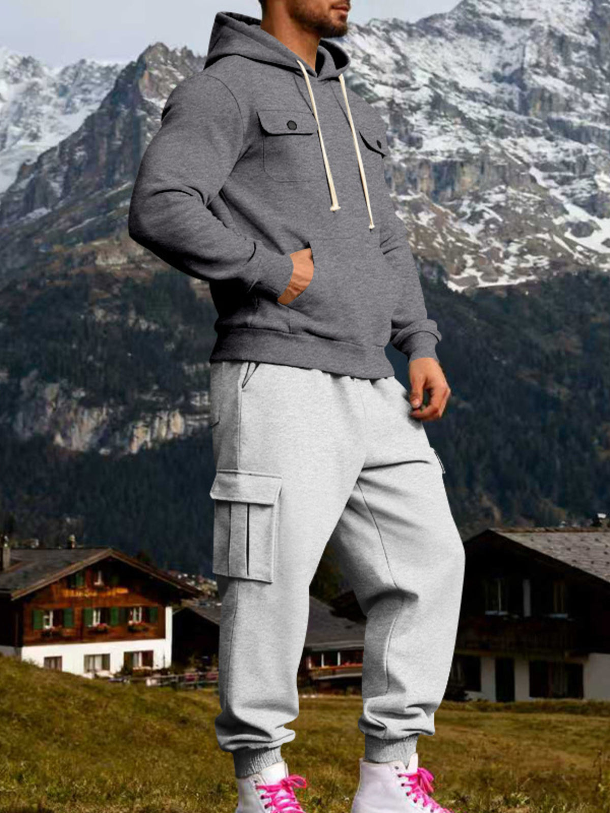 Model wearing a charcoal grey hoodie and light grey cargo joggers in an angled outdoor view