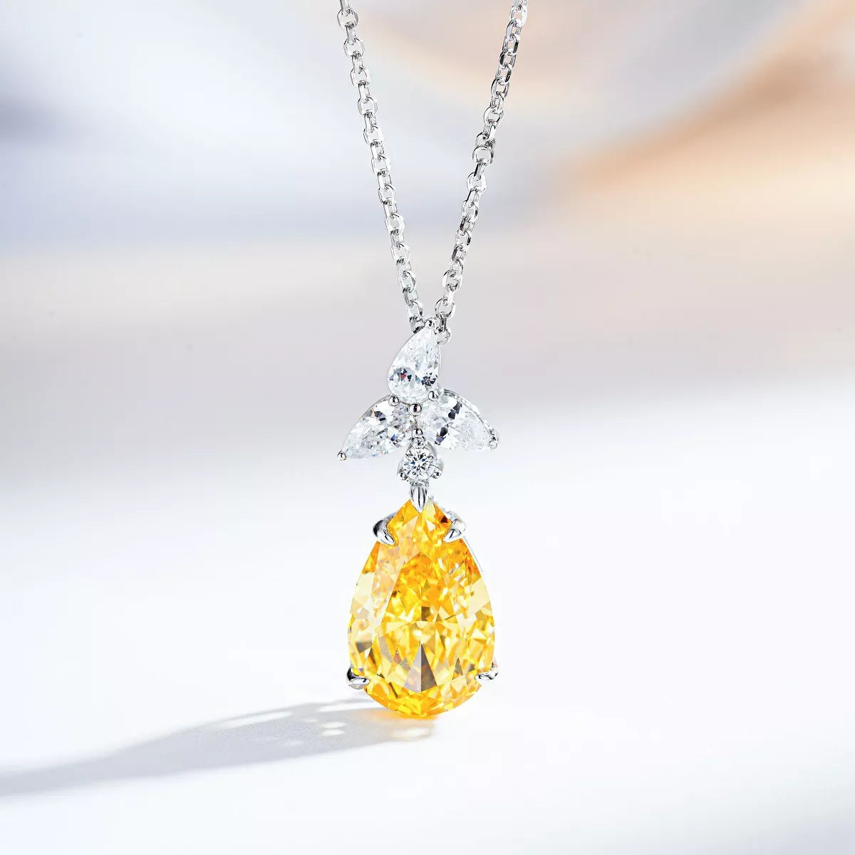 Light-yellow teardrop zircon pendant with a clear-stone accent on a silver-tone chain