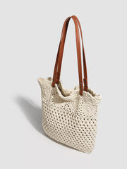 Angled view of the crochet tote showing its brown shoulder handles and open-knit side.