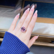 Pink rectangular gemstone ring with clear side accents shown on a hand