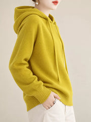 Side-front view of the mustard-yellow sweater with one hand in a trouser pocket.