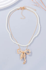 Full white beaded necklace with a gold-tone bow pendant and extension chain