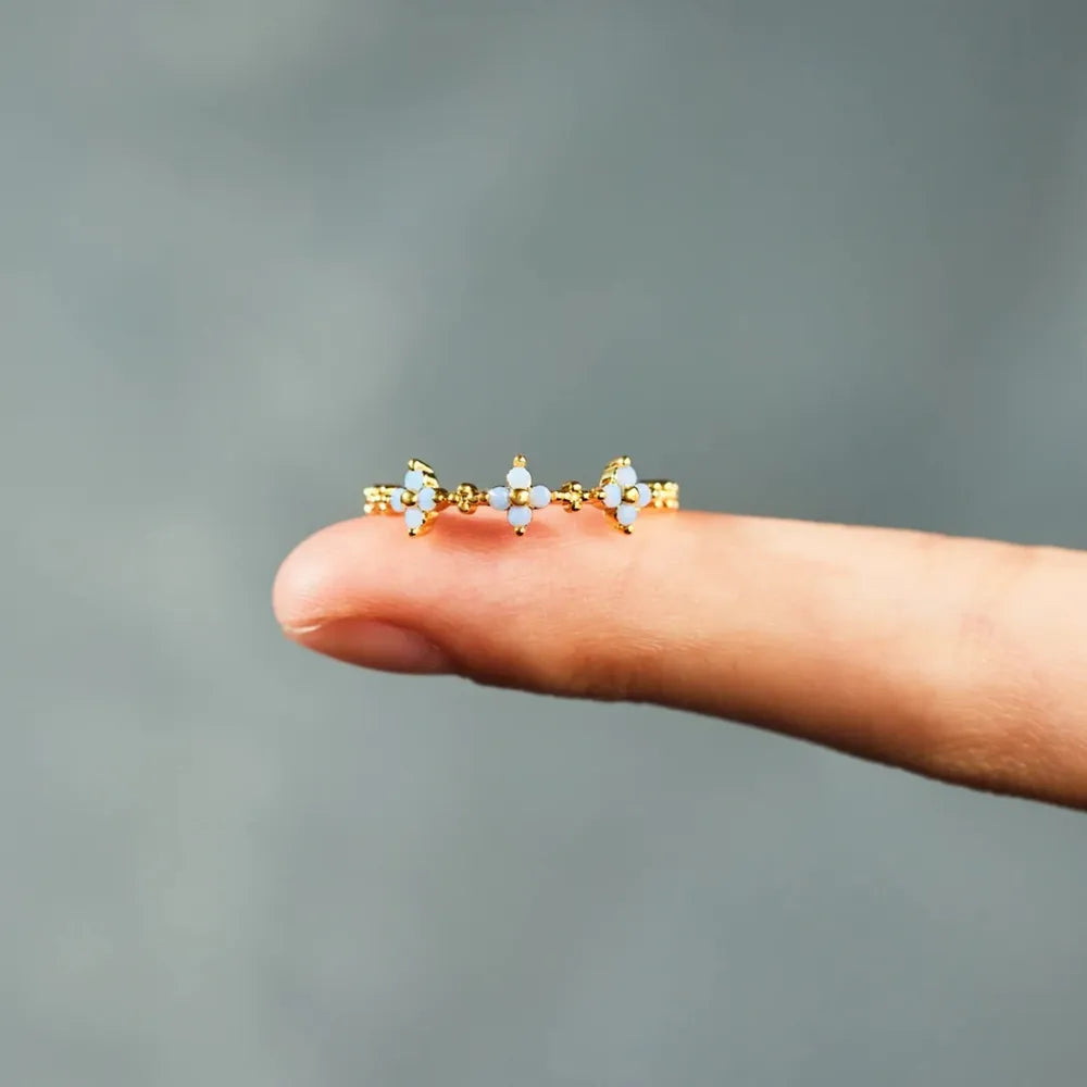 Flower ring balanced on a fingertip, showing raised stones