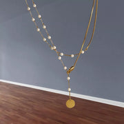 Close-up of pearl accents and gold-tone chain with coin pendant
