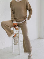 Taupe sweater and pants set shown seated on a stool, holding a takeaway cup.