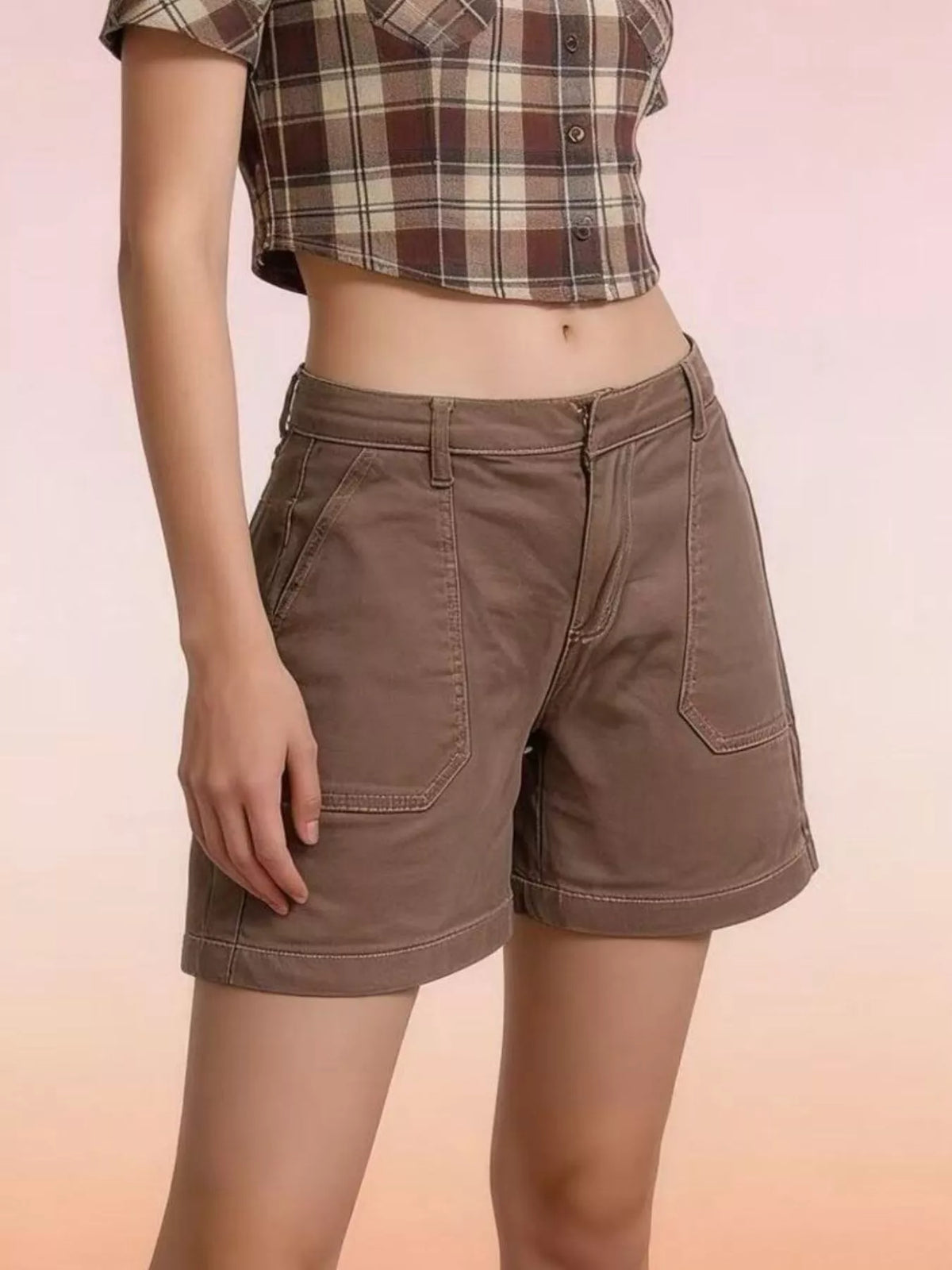 Angled view of brown denim shorts showing front patch pockets and stitched hems