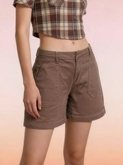 Angled view of brown denim shorts showing front patch pockets and stitched hems