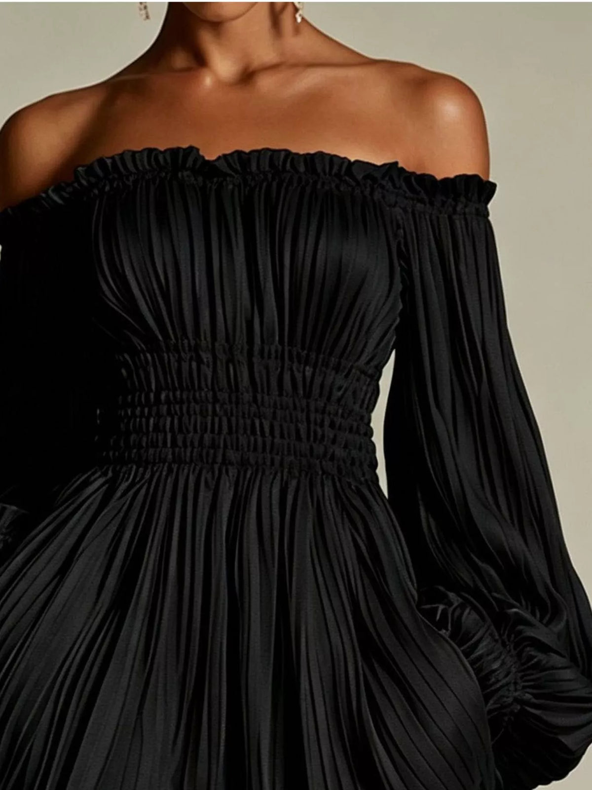 Model wearing the black version of the off-shoulder pleated mini dress