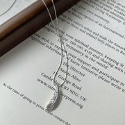 Feather pendant necklace arranged over an open book