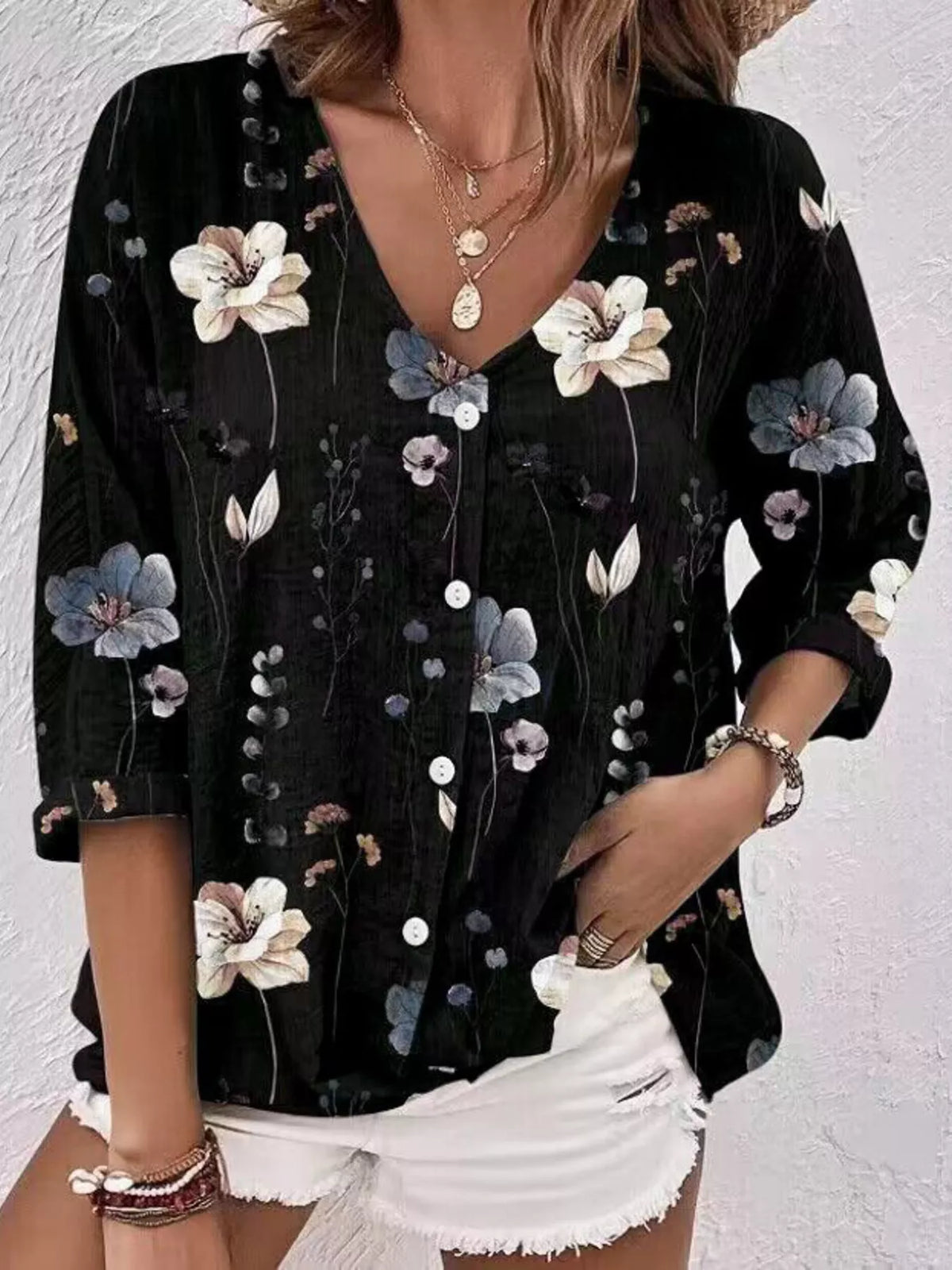 Model wearing black blouse with white and blue floral print.