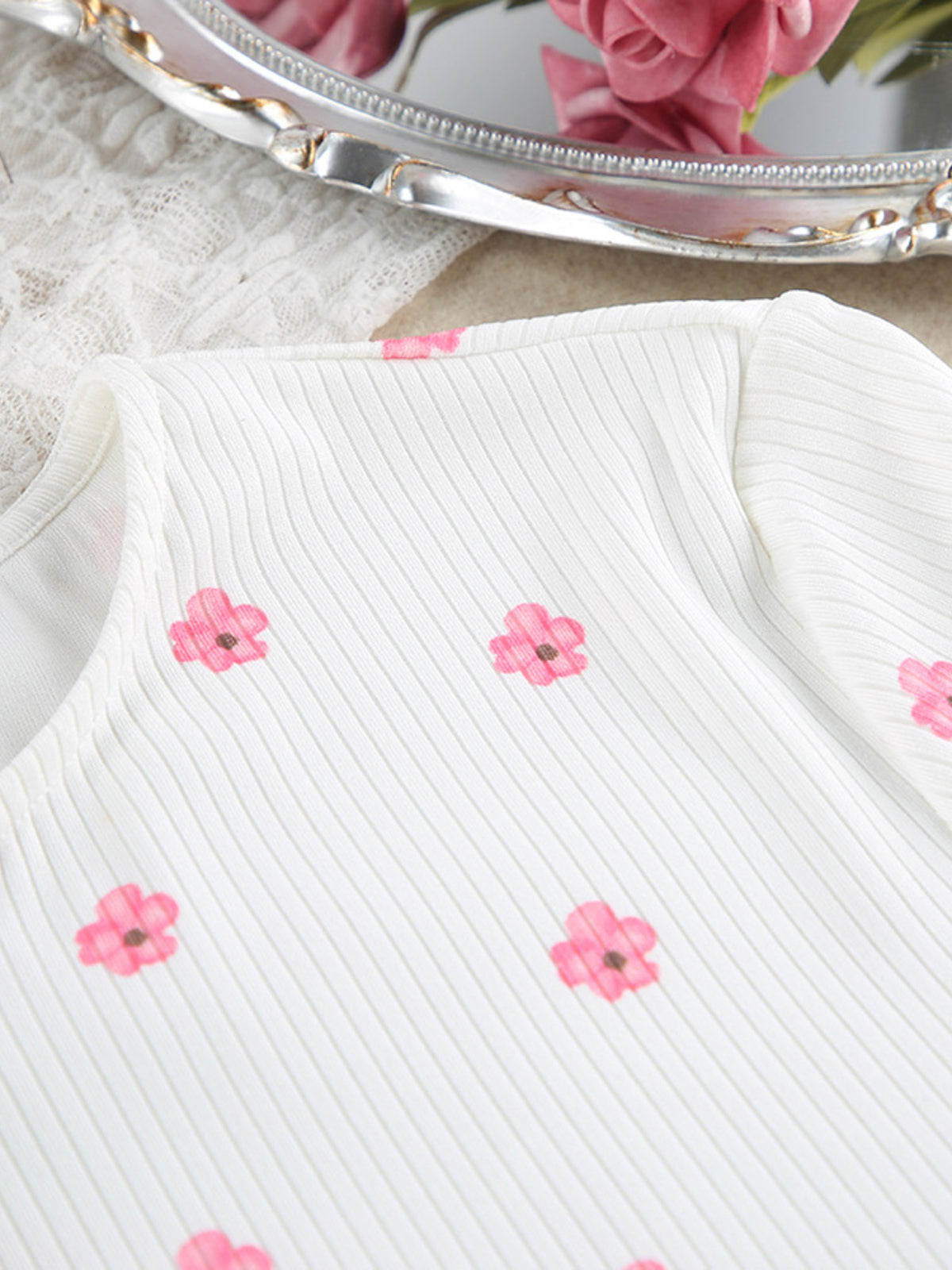 White ribbed top with pink flower print laid flat, neckline and button placket