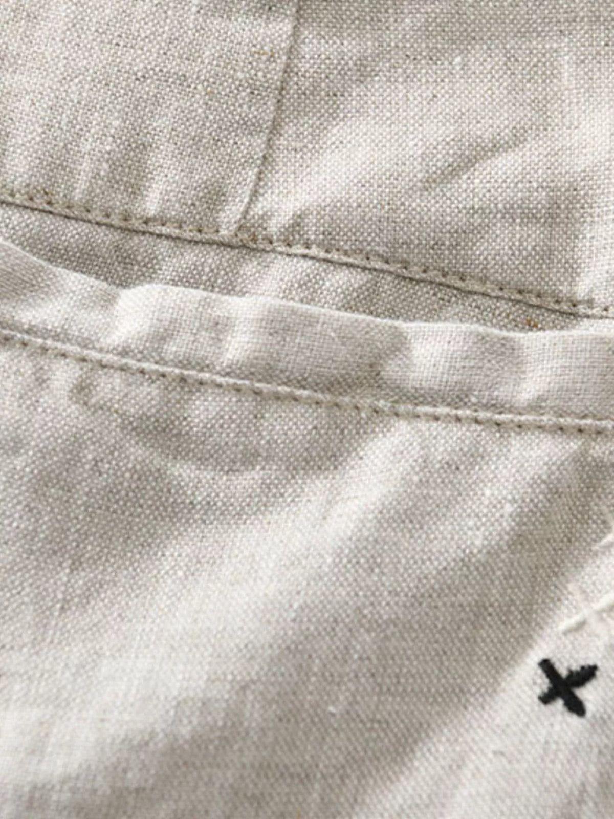 Close-up of white shorts pocket and small embroidered mark