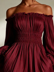 Model wearing the burgundy version of the pleated off-shoulder dress