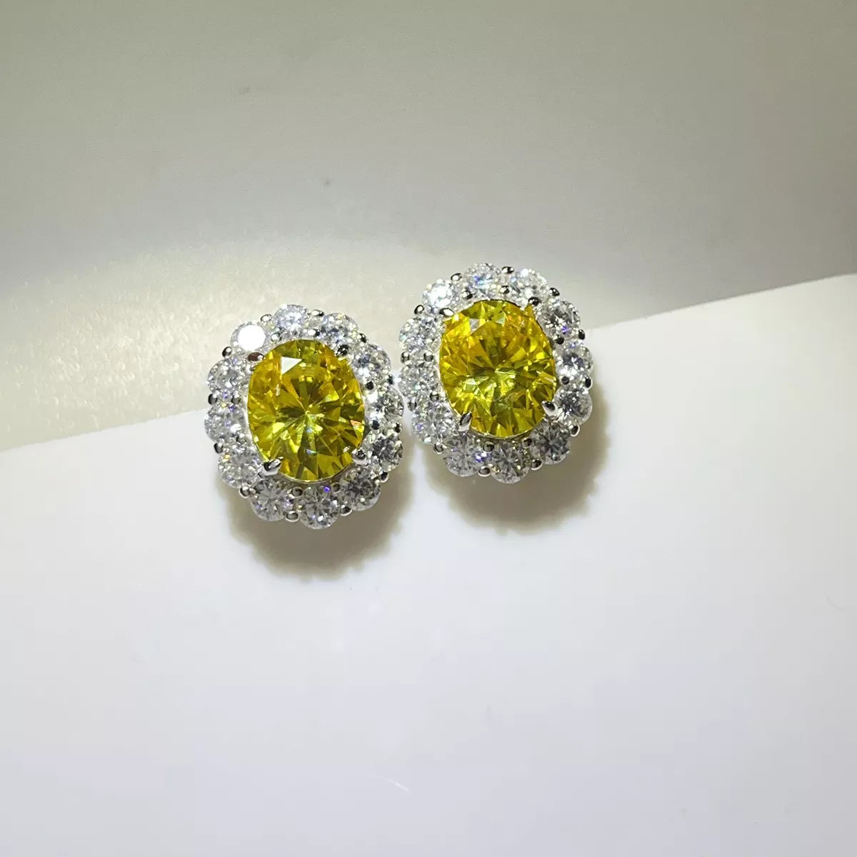Yellow oval moissanite studs shown together on a light surface.
