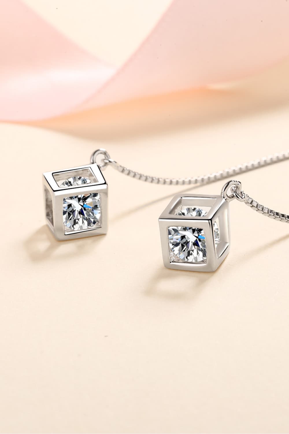 Close-up of square clear-stone drops and fine chains on threader earrings