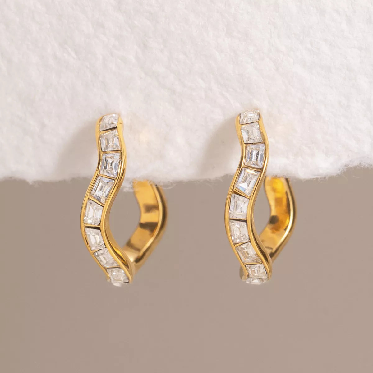 Close-up of the square zircon accents on gold-tone hoop earrings