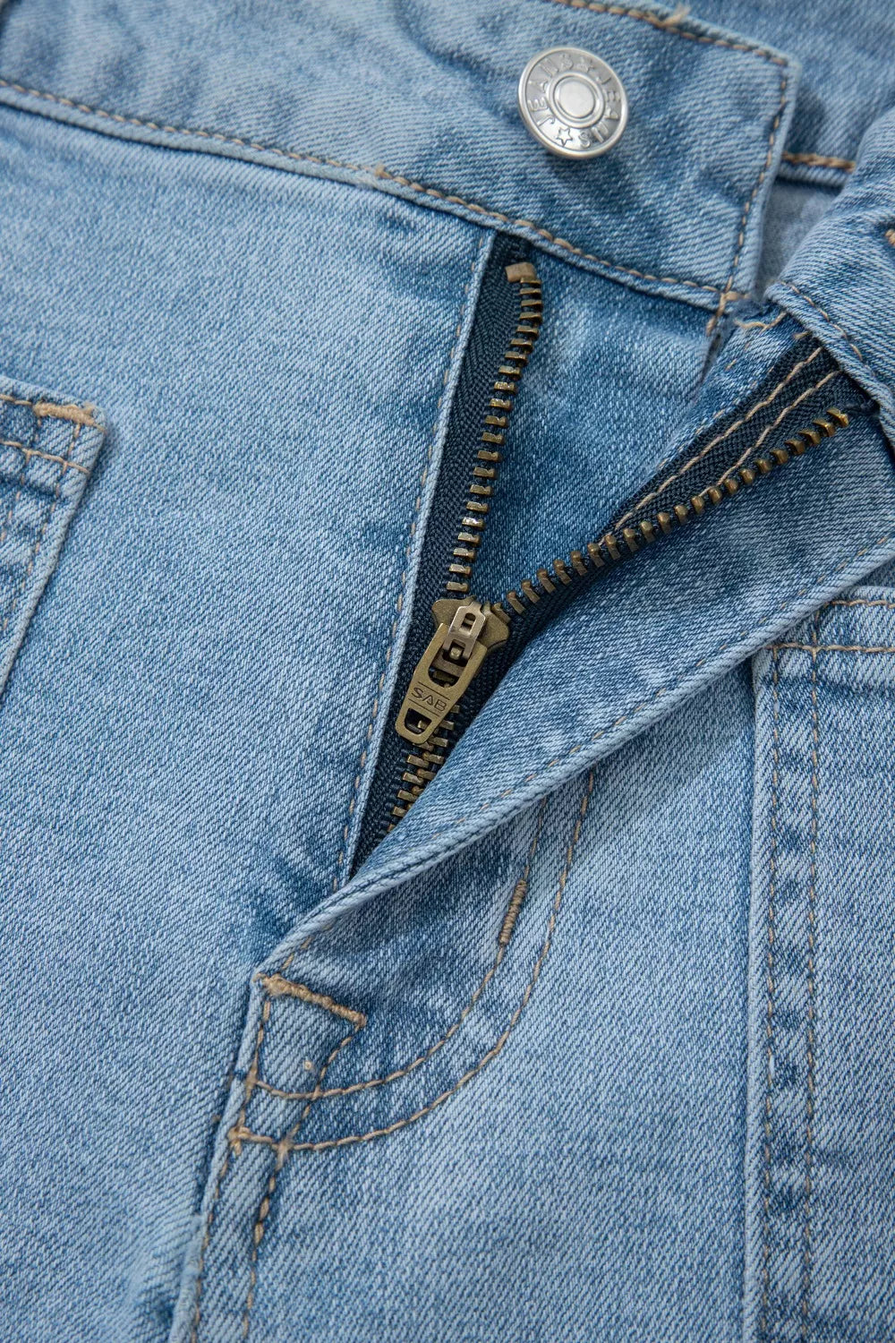 Close-up of front patch pocket and button on denim shorts