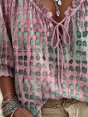 Close view of pink blouse with green spots, ruffled neckline and tied front