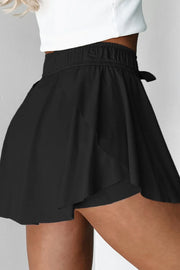 Side view of black skort with flared overlay over fitted shorts