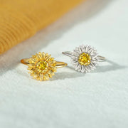 Gold-tone and silver-tone sunflower rings with yellow center stones on fabric