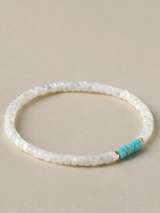White rectangular beads form a bracelet with a turquoise bead section and gold-tone spacers