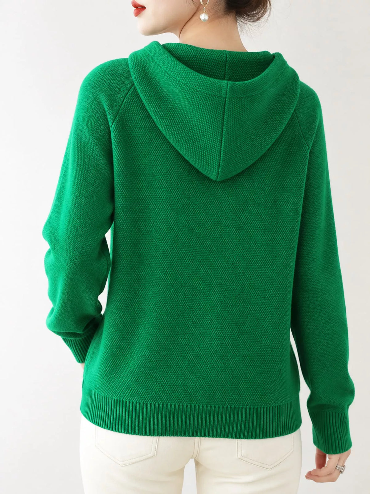 Back view of the emerald green knit sweater showing its hood and ribbed hem.