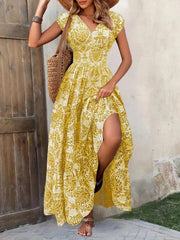 Blue floral maxi dress with a thigh-high slit, shown on a model holding the skirt aside.