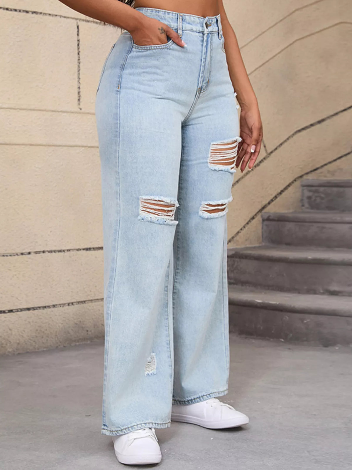 Opposite angled view of light-wash wide-leg jeans showing thigh and knee distressing