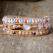 Front view of a multistrand pastel bead bracelet with a pink teardrop centerpiece on rustic wood