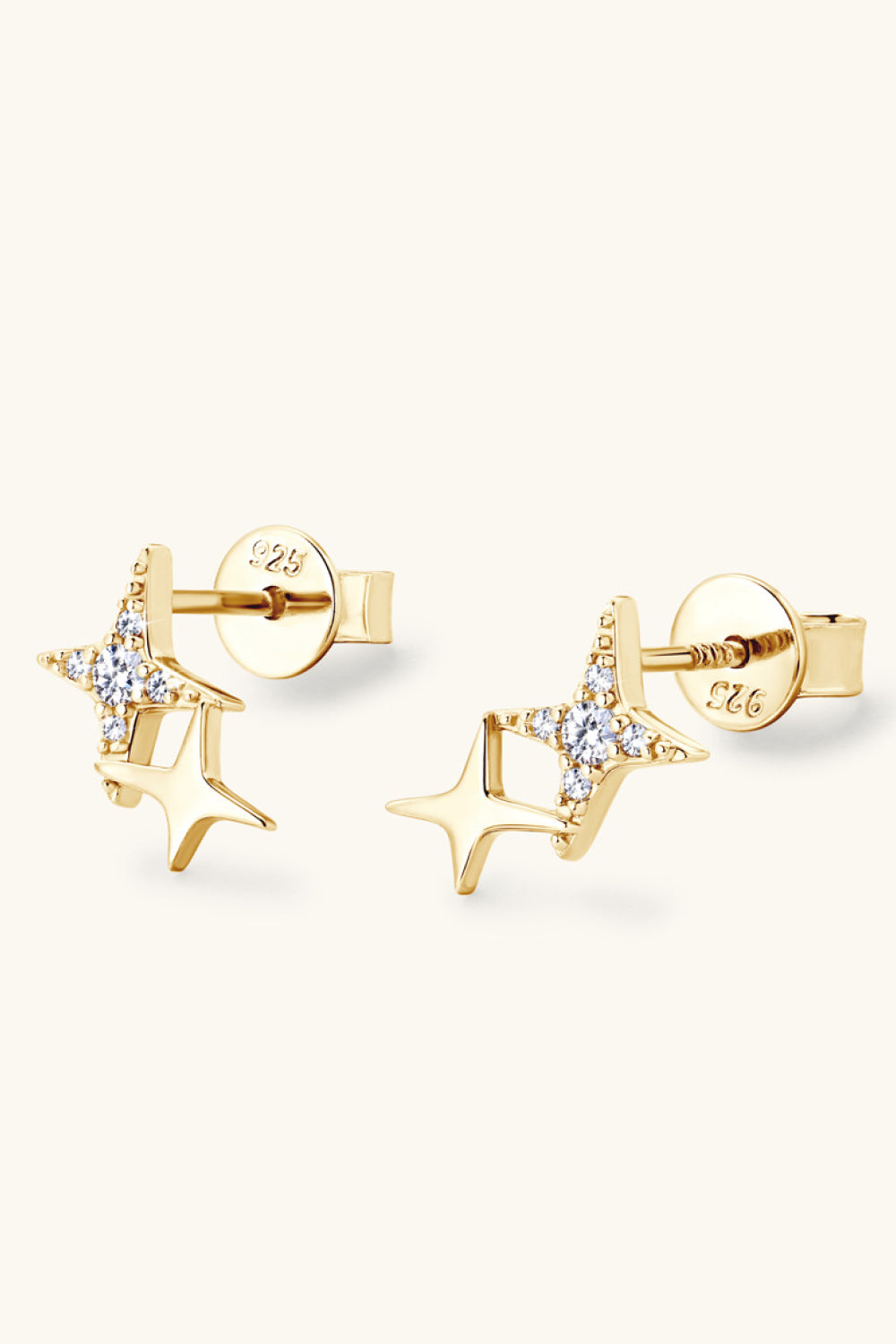 Gold-tone star-shaped stud earrings resting at an angle on a pale background