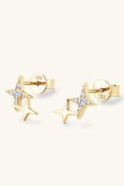 Gold-tone star-shaped stud earrings resting at an angle on a pale background
