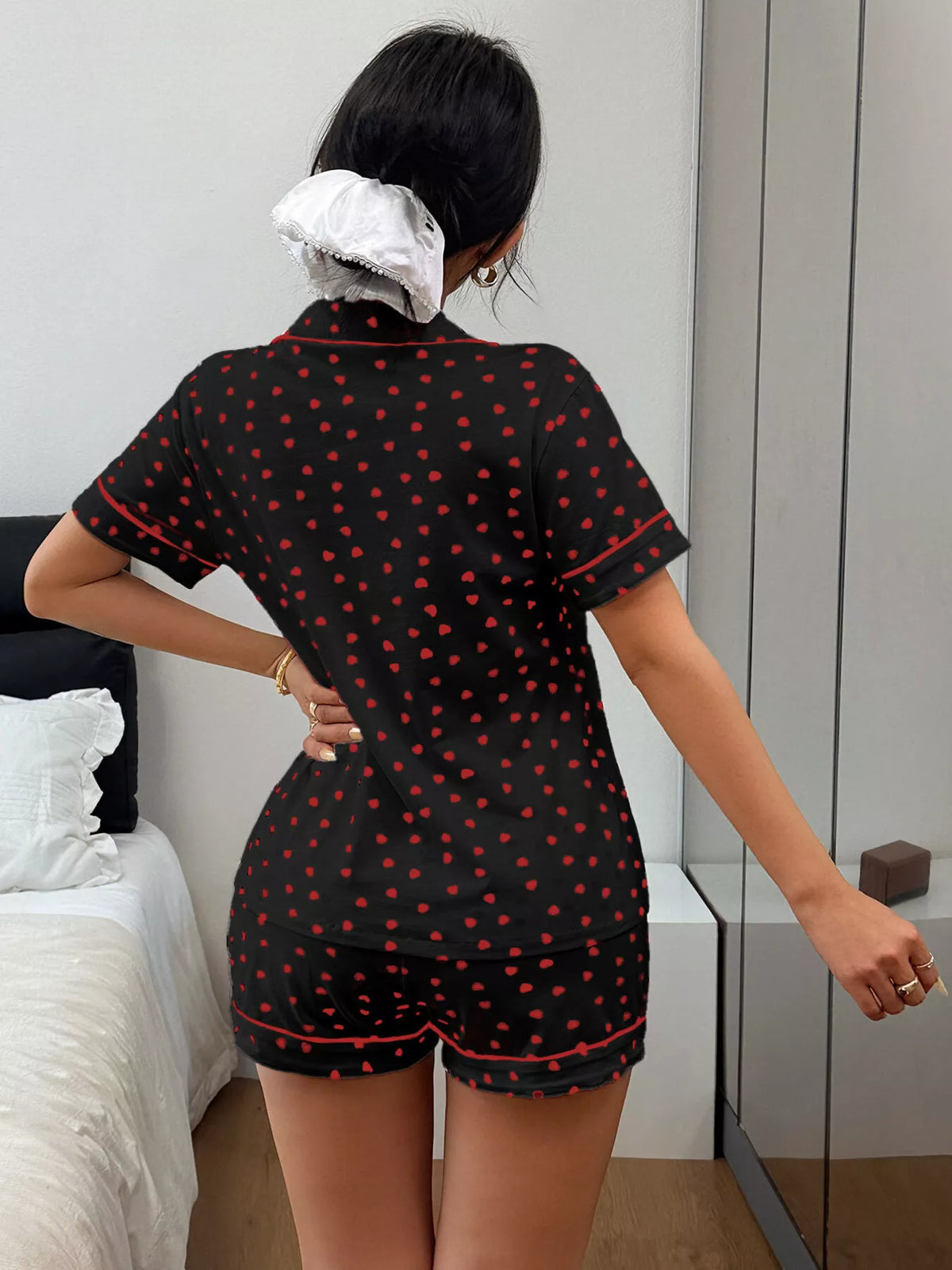 Model seated in black pajamas with scattered red hearts