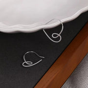 Pair of sterling silver heart-shaped dangle earrings on a dark display