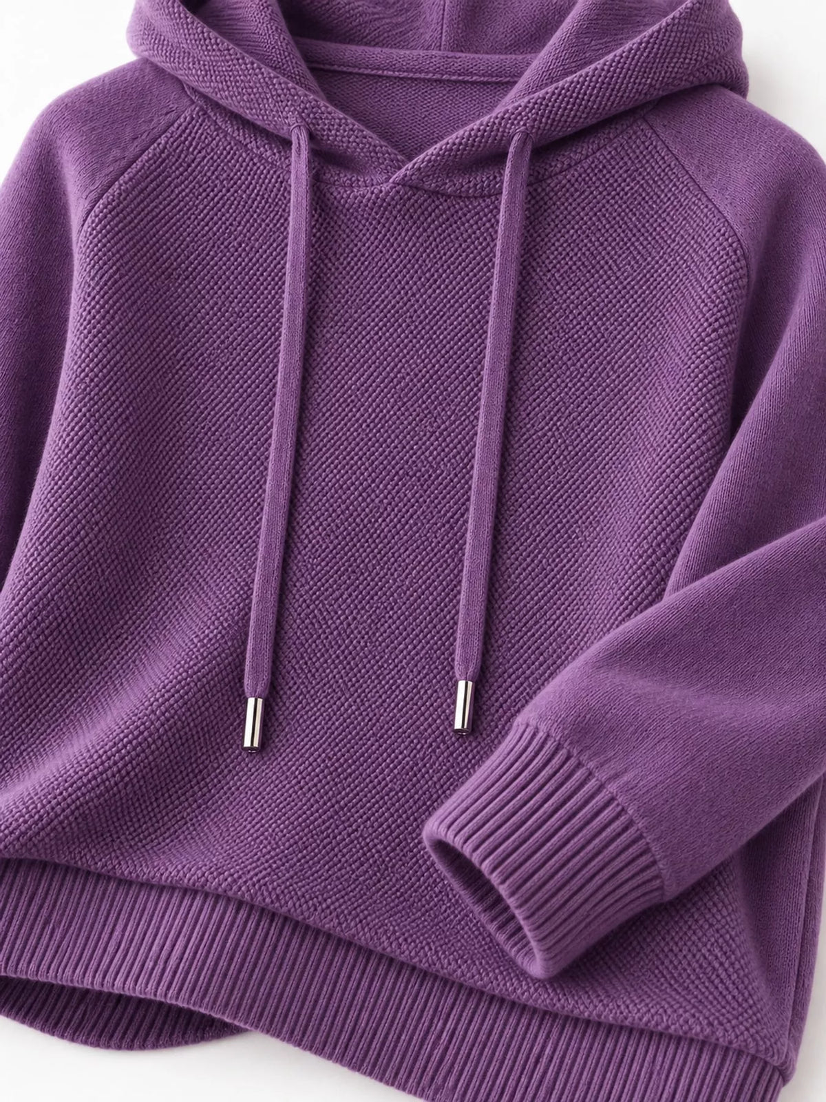 Purple sweater close-up showing the hood opening, metal-tipped drawstrings and ribbed cuff.