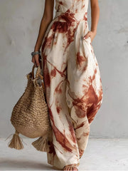 Lower view of the rust-print jumpsuit showing wide legs and a side pocket.