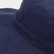 Close-up of the navy bucket hat's stitched crown and brim.